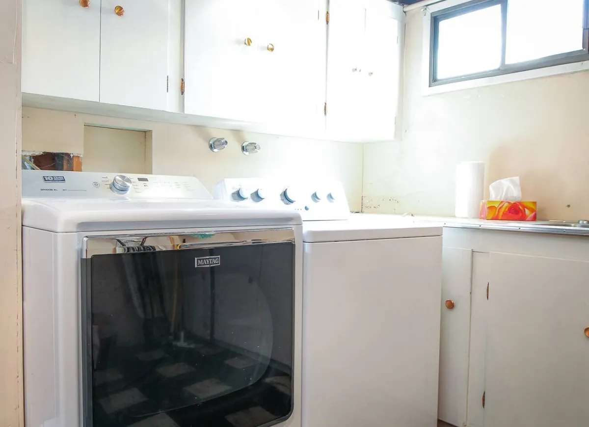 A practical laundry area with a washer and dryer, cabinets for storage, and a countertop for folding. The space is bright, clean, and organized, supporting daily routines.
