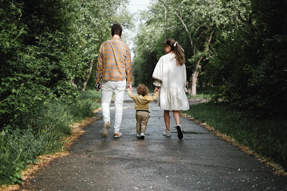 A family, including a child and a dog, walks together along a lush green pathway. The scene radiates a sense of joyful togetherness, emphasizing outdoor activity and pet-friendliness.